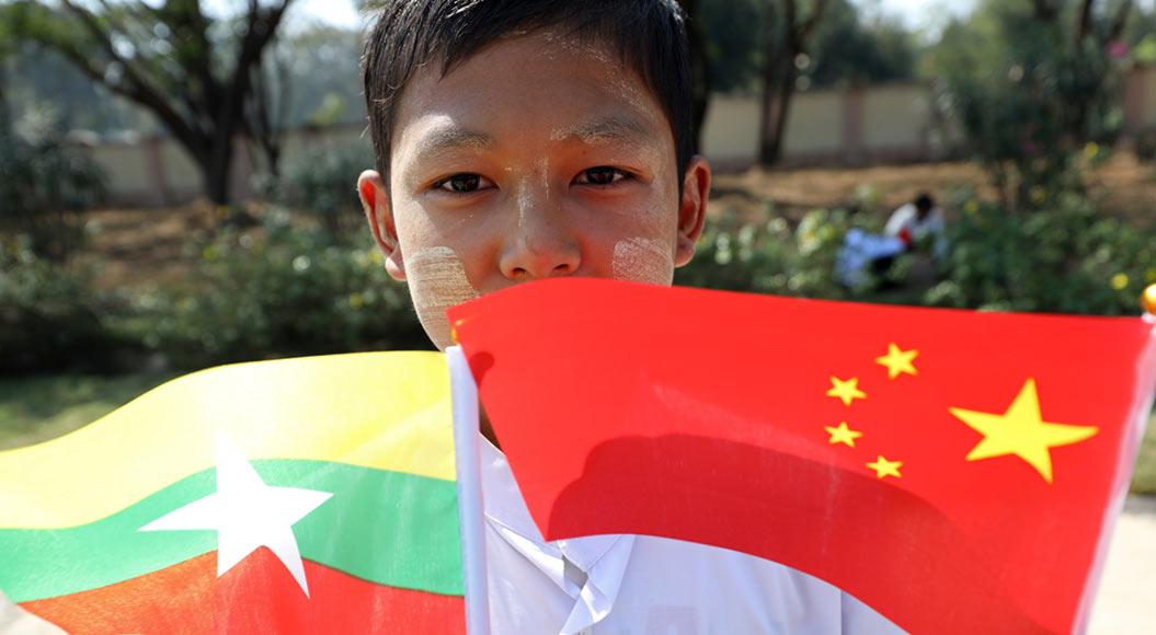  Ein Schüler aus Myanmar hält eine myanmarische und chinesische Flagge.